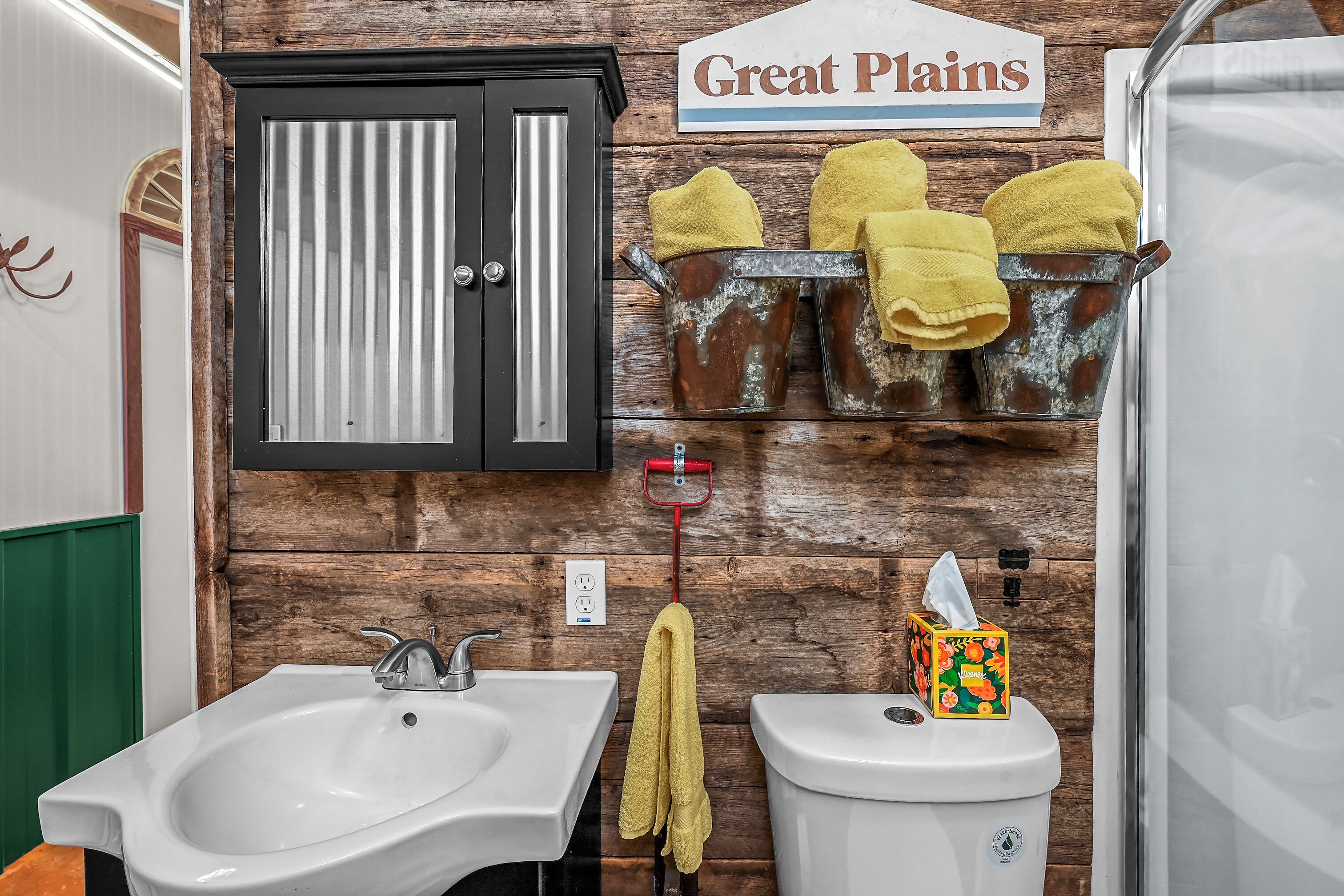 A bathroom with a wooden wall, a sink, a toilet, and a cabinet.
