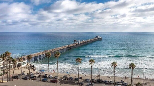A pier extending into the ocean with a beach area in the foreground.