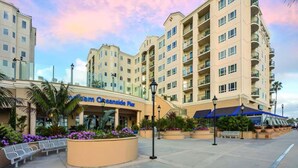 A hotel with multiple floors, outdoor seating, and a palm tree.
