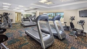 A hotel fitness center with treadmills, elliptical machines, and free weights.
