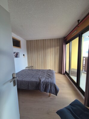 A bedroom with a bed, a window, and a door. - Spacious apartment in Orcières Merlette with stunning mountain views (Merlette Orcières)