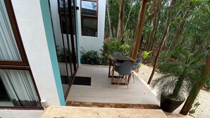 A rectangular pool with a mosaic tile design, surrounded by a concrete deck and a small patio area with a table and chairs. - Baalamkaab Flamenco Studio (Chichimilá)