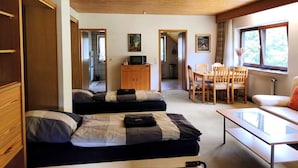 Una habitación con dos camas, una mesa de comedor con sillas, un armario de madera y una ventana con vistas.