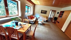 Un comedor acogedor con una mesa y sillas de madera, un sofá y un televisor en una sala de estar.