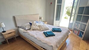 A bedroom with a wooden bed, a nightstand, a lamp, and a bookshelf. - Charming 1920s house in Nice district (Nice)