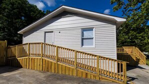 Een gelijkvloers huis met een veranda en een houten trap naar de ingang.