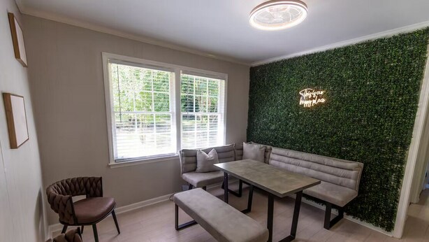 Een moderne woonkamer met een groene wand, een bank, een tafel en twee stoelen.
