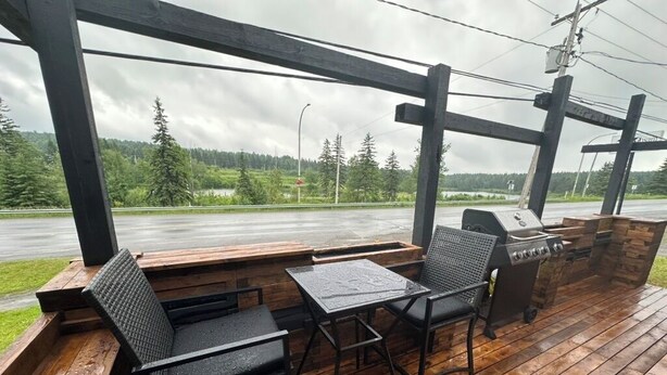 Eine Terrasse im Freien mit Holzboden, Grill und Sitzgelegenheiten.