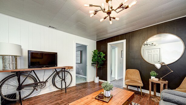 Una sala de estar moderna con una televisión, una bicicleta, un espejo redondo y una mesa de centro.