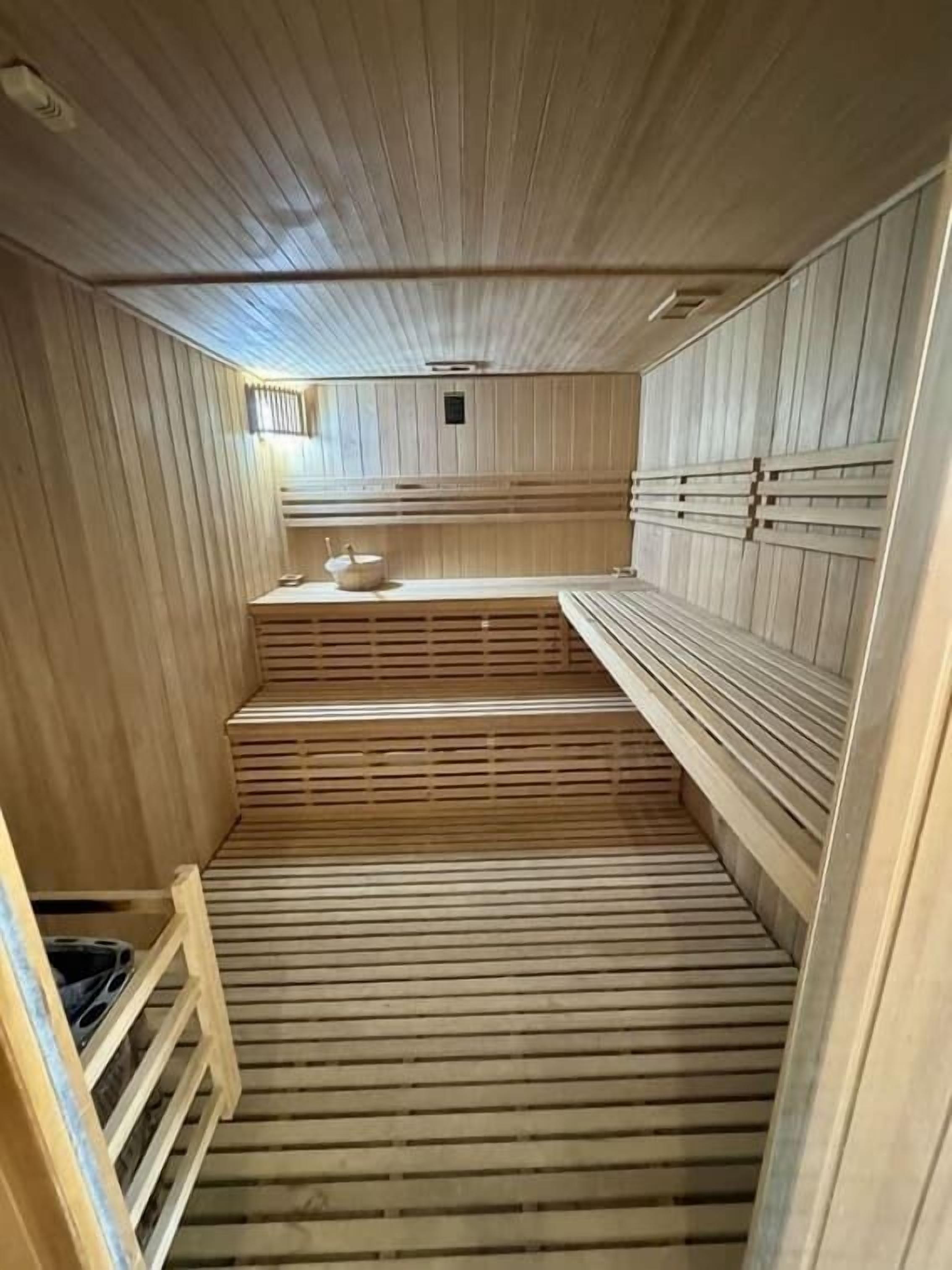 A sauna with wooden benches and a sloped floor.