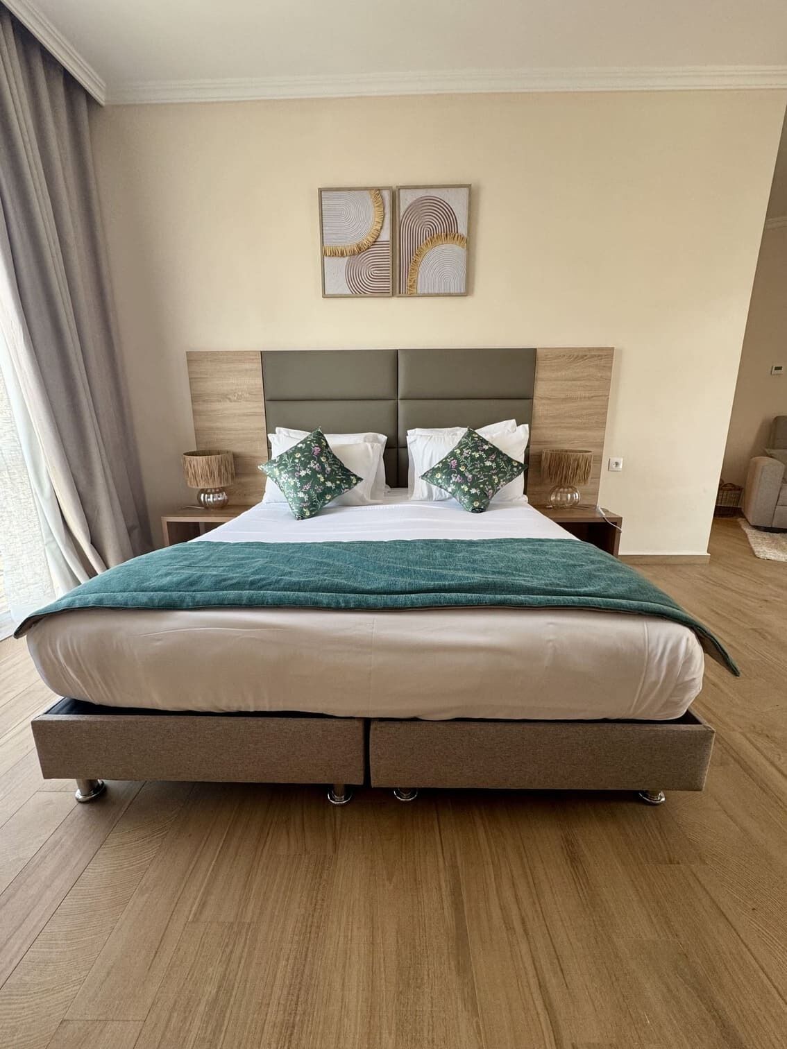 A spacious bedroom with a large bed, two nightstands, and a headboard with a decorative panel.