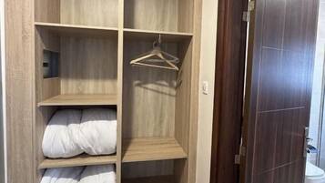 Un dressing avec de nombreuses étagères et un espace pour suspendre les vêtements, un plancher en bois et une porte en bois foncé.