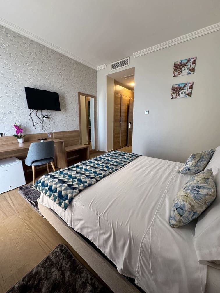 Un dormitorio con cama, escritorio, silla, televisor y armario.