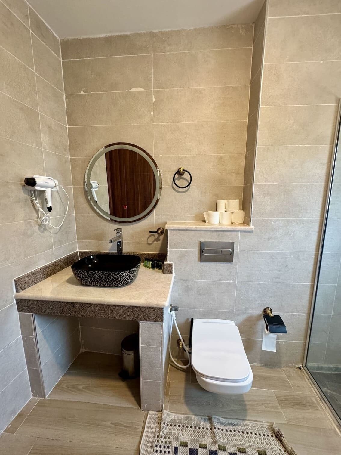 A bathroom with a sink, mirror, toilet, and shower.