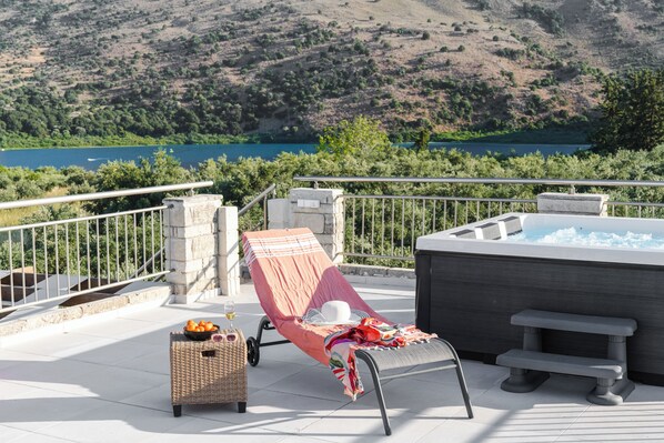 A balcony with a lounge chair, a hot tub, and a wicker basket with fruits. - Lithus Retreat with Jacuzzi  & 360° Views (ΧΑΝΙΑ)
