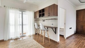 A modern kitchen with wooden cabinets, a white countertop, and two bar stools.
