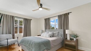 A bedroom with a bed, bedside table, lamp, and curtains. - Modern Poolside Bungalow in the Heart of Orlando (Orlando)