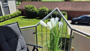 Un balcon avec une chaise noire, une table en bois, une bouteille de vin et un verre.