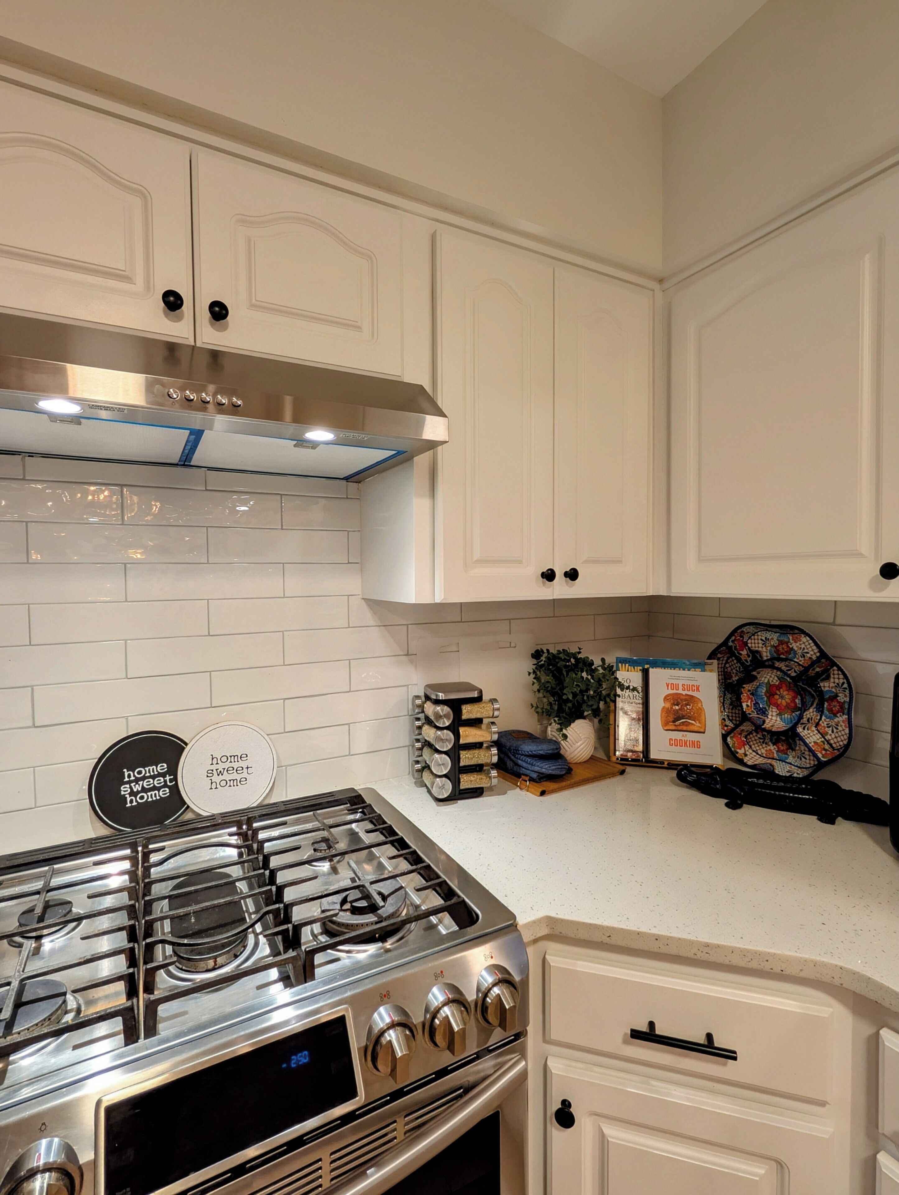 A kitchen with white cabinetry, a stainless steel stove, and a backsplash.