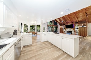 Una cocina moderna con armarios blancos, techo de madera y chimenea de piedra.