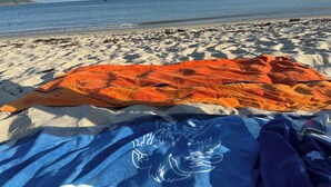 Ein Strand mit Decke und Handtuch, die im Sand liegen.