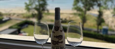 Una bottiglia di vino Albarino e due bicchieri su un davanzale con vista sulla spiaggia.