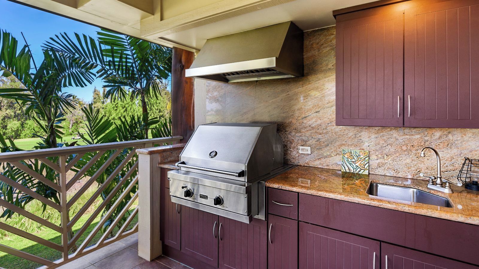 An outdoor kitchen with a grill, a sink, and cabinets.