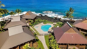 A resort with multiple buildings, a swimming pool, and a view of the ocean.