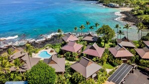 A coastal resort with multiple bungalow-style buildings, a swimming pool, and a view of the ocean.