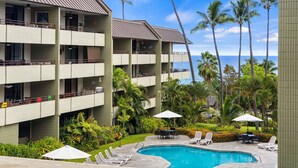 Un hotel con piscina, sillas de descanso y palmeras.