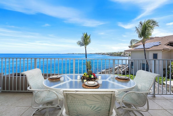 A round table with white chairs on a balcony overlooking a coastal view. - Ocean Front - Direct View of Kailua Bay - Vrkcv (Kailua-Kona)