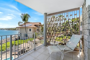 A balcony with a view of the sea, a pool, and a house in the background. - Ocean Front - Direct View of Kailua Bay - Vrkcv (Kailua-Kona)