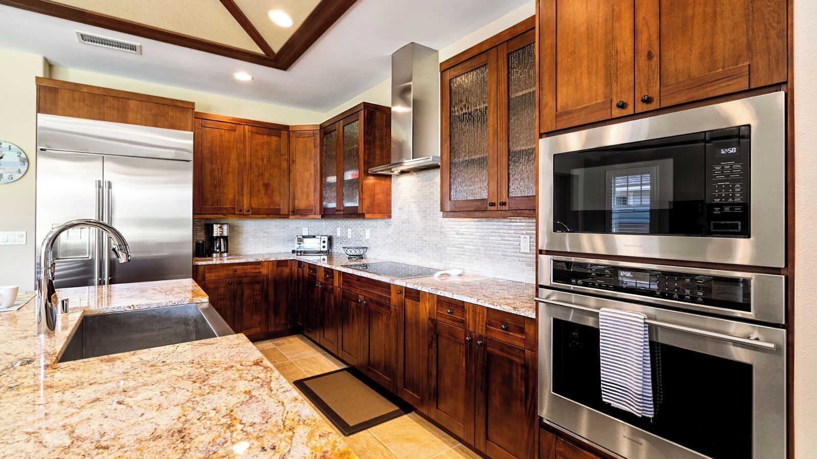 A modern kitchen with wooden cabinets, stainless steel appliances, a granite countertop, and a built-in microwave.
