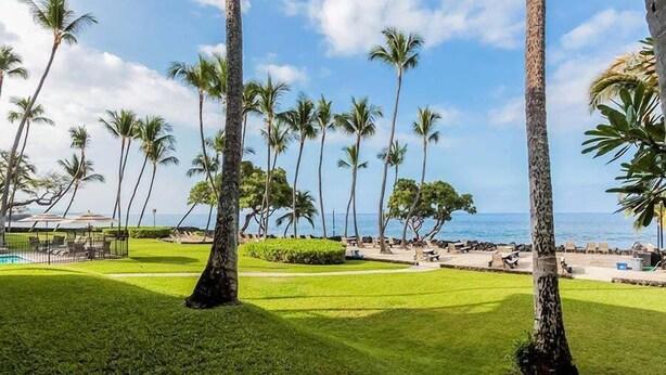 A tropical resort with palm trees, a pool, and a view of the ocean. - Private Ground Floor Corner Unit - AC & Hawaiian Ocean Views - Vrkcv (Kailua-Kona)