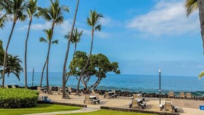A beachside resort with palm trees, lounge chairs, and a view of the ocean. - Private Ground Floor Corner Unit - AC & Hawaiian Ocean Views - Vrkcv (Kailua-Kona)