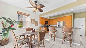 A spacious kitchen with wooden cabinets, a central island with bar stools, and a ceiling fan. - Family-friendly - Pools & Bbqs - Concierge Service - Vrkcv (Waikoloa)