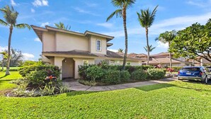 A two-story house with a well-maintained lawn, palm trees, and a parked car. - Family-friendly - Pools & Bbqs - Concierge Service - Vrkcv (Waikoloa)