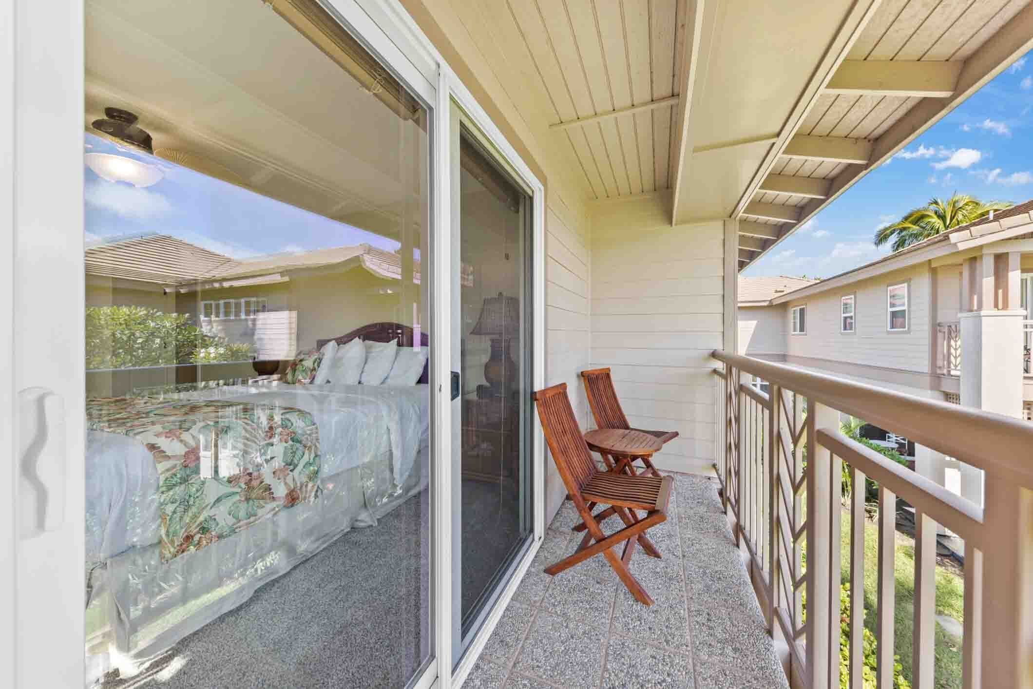 Un balcón con una cama, una silla y vistas a casas vecinas.