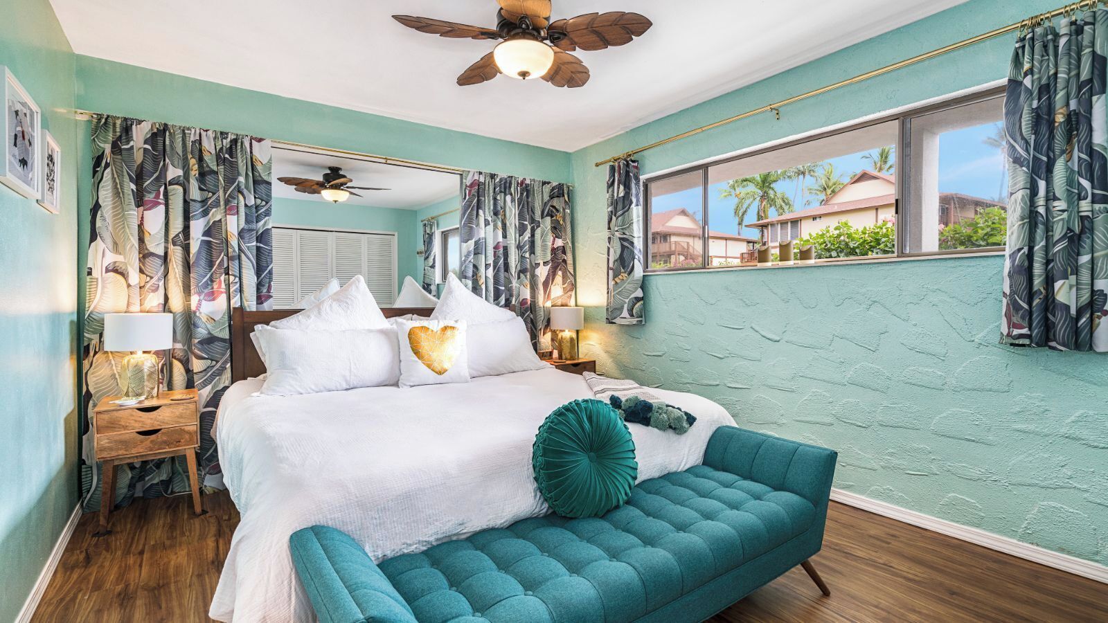 A bedroom with a bed, a bench, a ceiling fan, and curtains.
