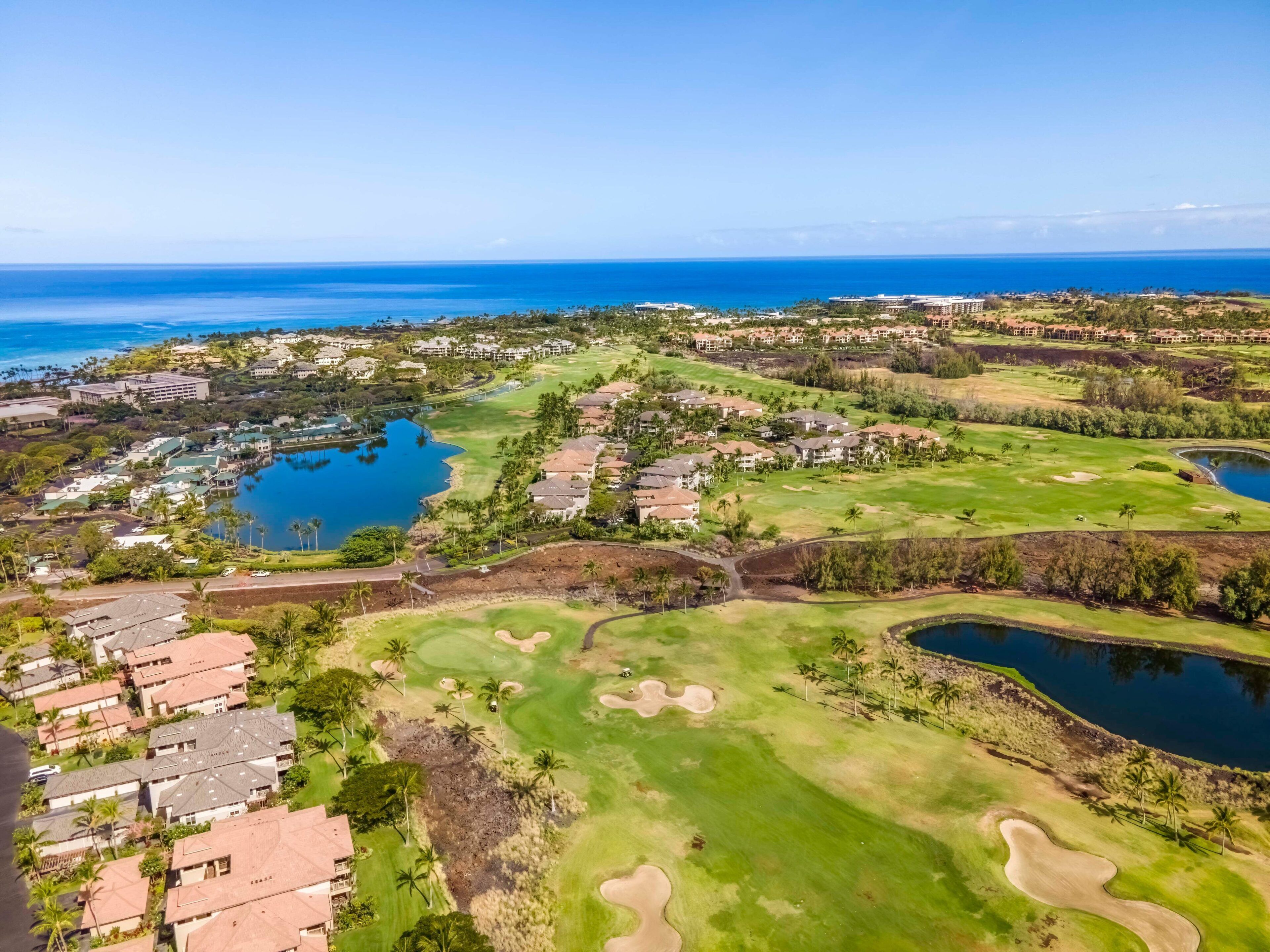 An aerial view of a golf course with multiple water bodies, residential areas, and a large hotel complex.