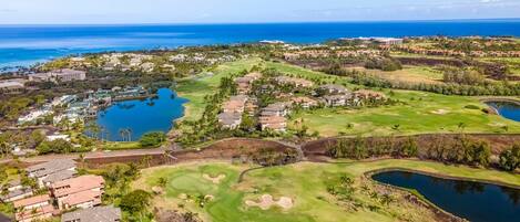 An aerial view of a golf course with multiple water bodies, residential areas, and a large hotel complex.