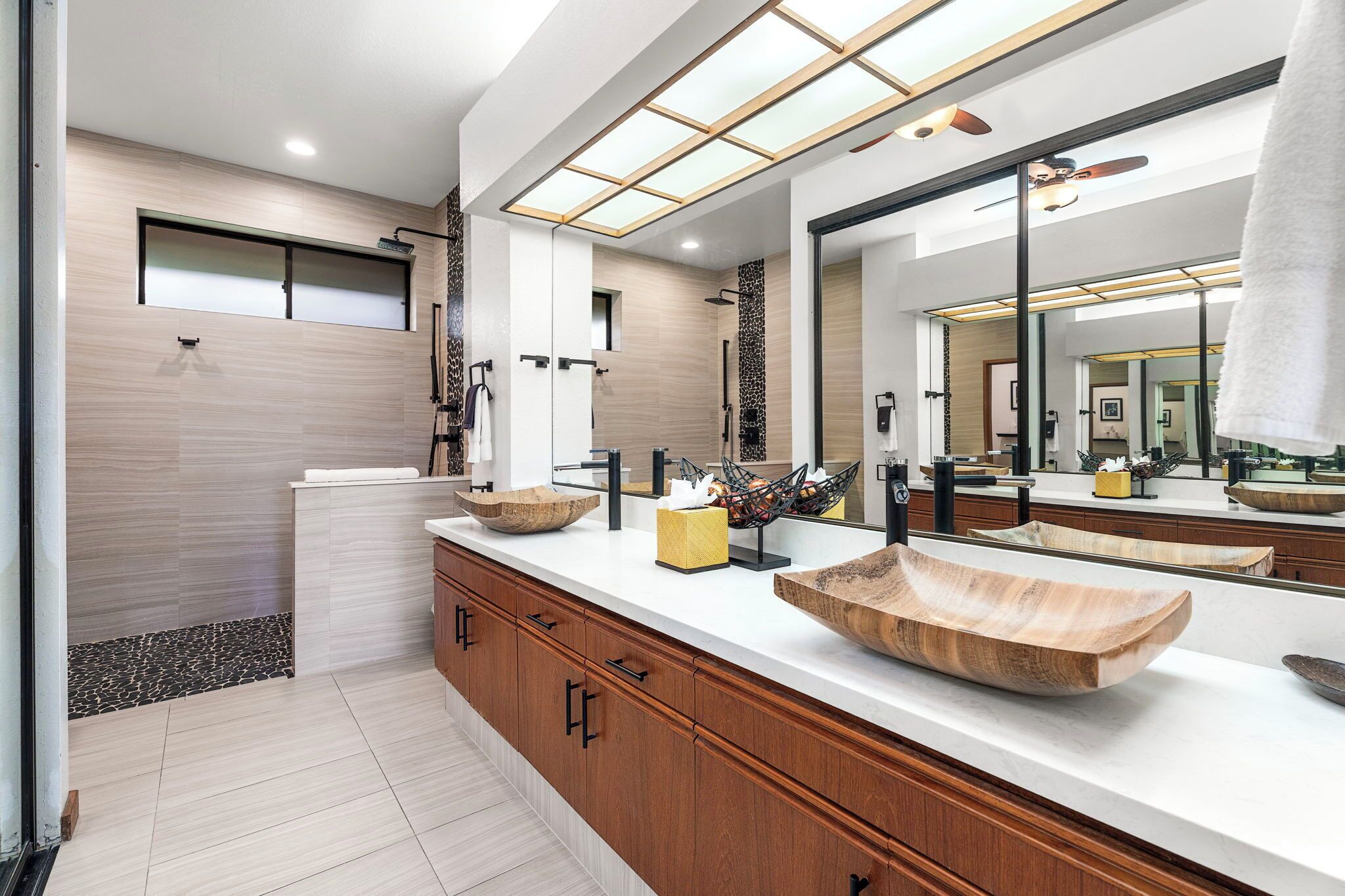 Un baño moderno con armarios de madera, un espejo grande y un lavamanos de madera.