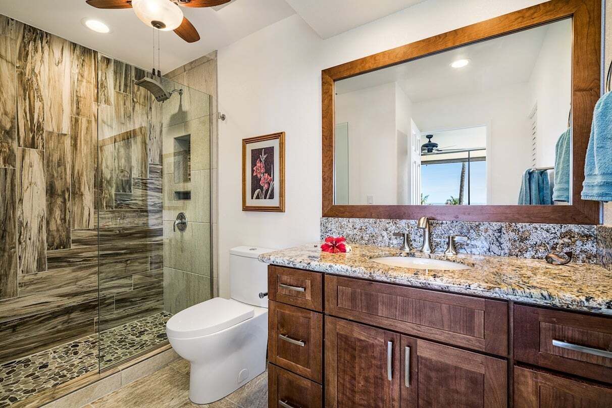 A bathroom with a marble vanity, a large mirror, and a shower with a glass door.