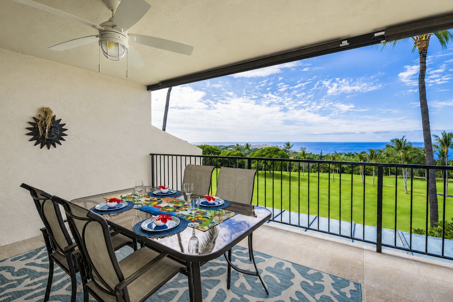 A dining table set for four with a view of the ocean and a golf course.