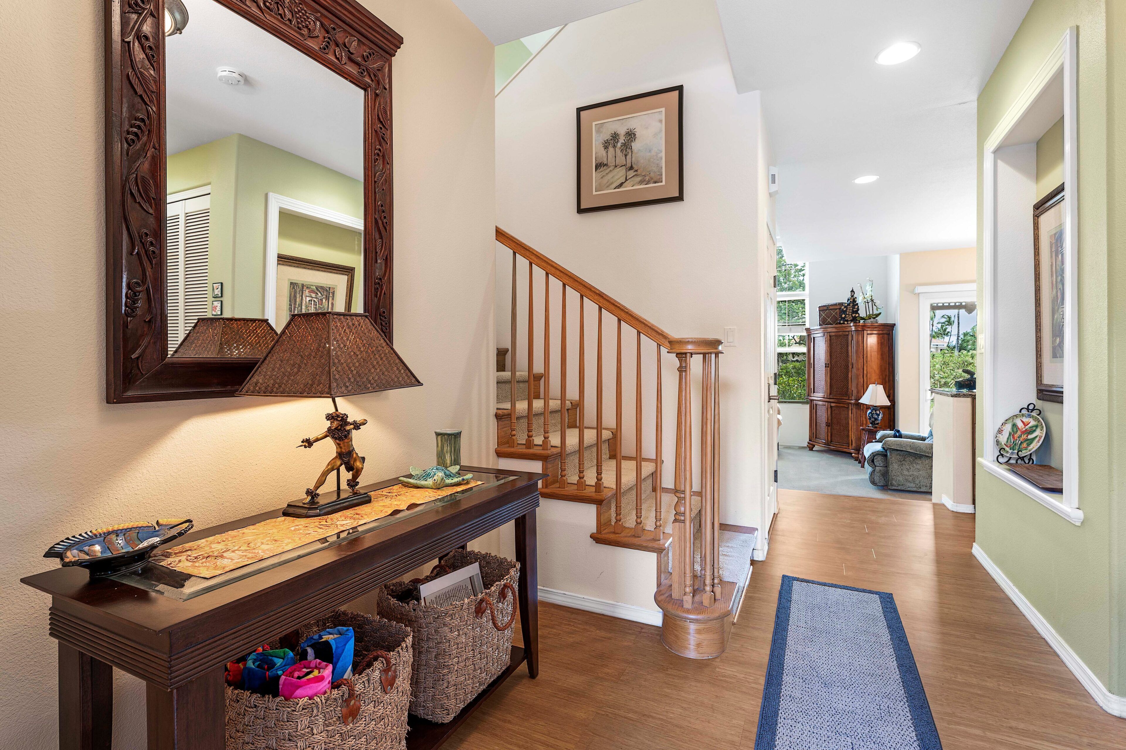 A wooden console table with a lamp, a mirror, and baskets. A wooden staircase leads to another room.