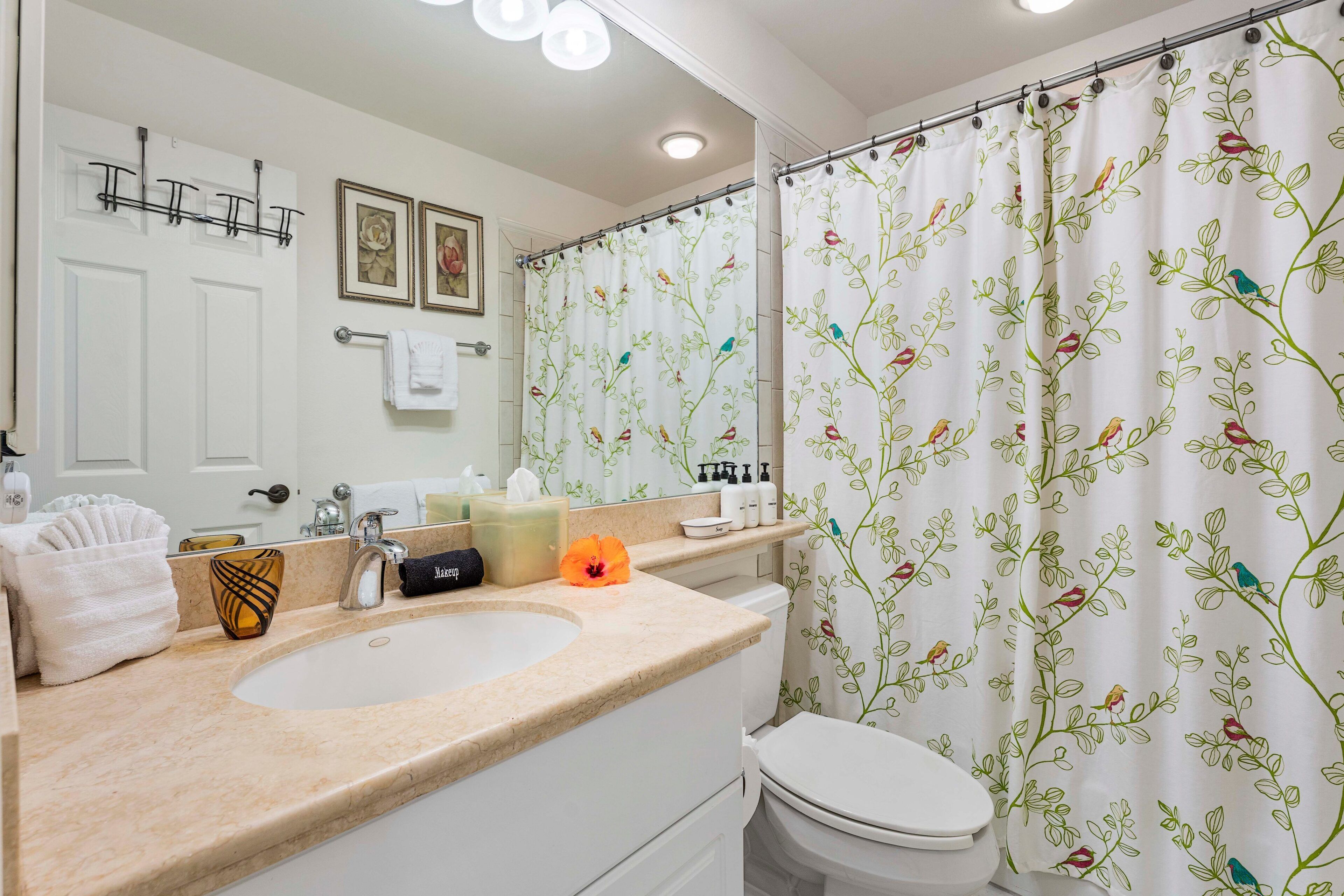 A bathroom with a sink, toilet, and shower curtain with a floral pattern.