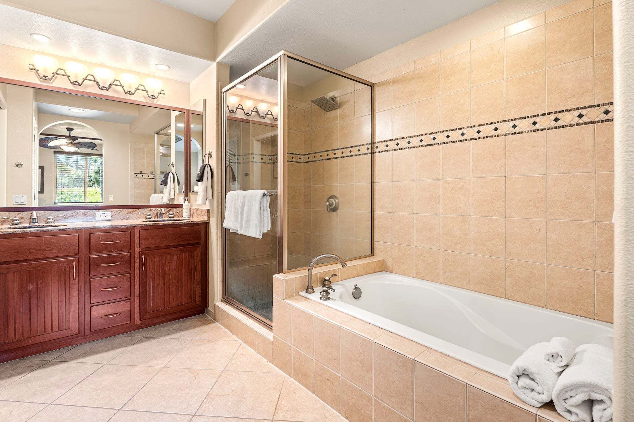Une salle de bain dotée d’un grand miroir, d’une douche, d’une baignoire et d’un meuble-lavabo avec des tiroirs.