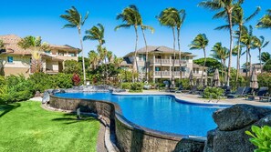 A swimming pool with lounge chairs and palm trees, surrounded by buildings. - Concierge Included - Ground Floor With Lake Views - Near Shopping Center - Vrkcv (Waikoloa)