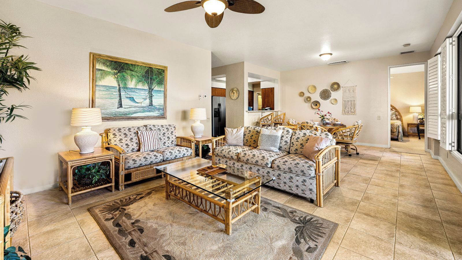 A spacious living room with a large sofa set, a coffee table, and a painting of a beach scene.
