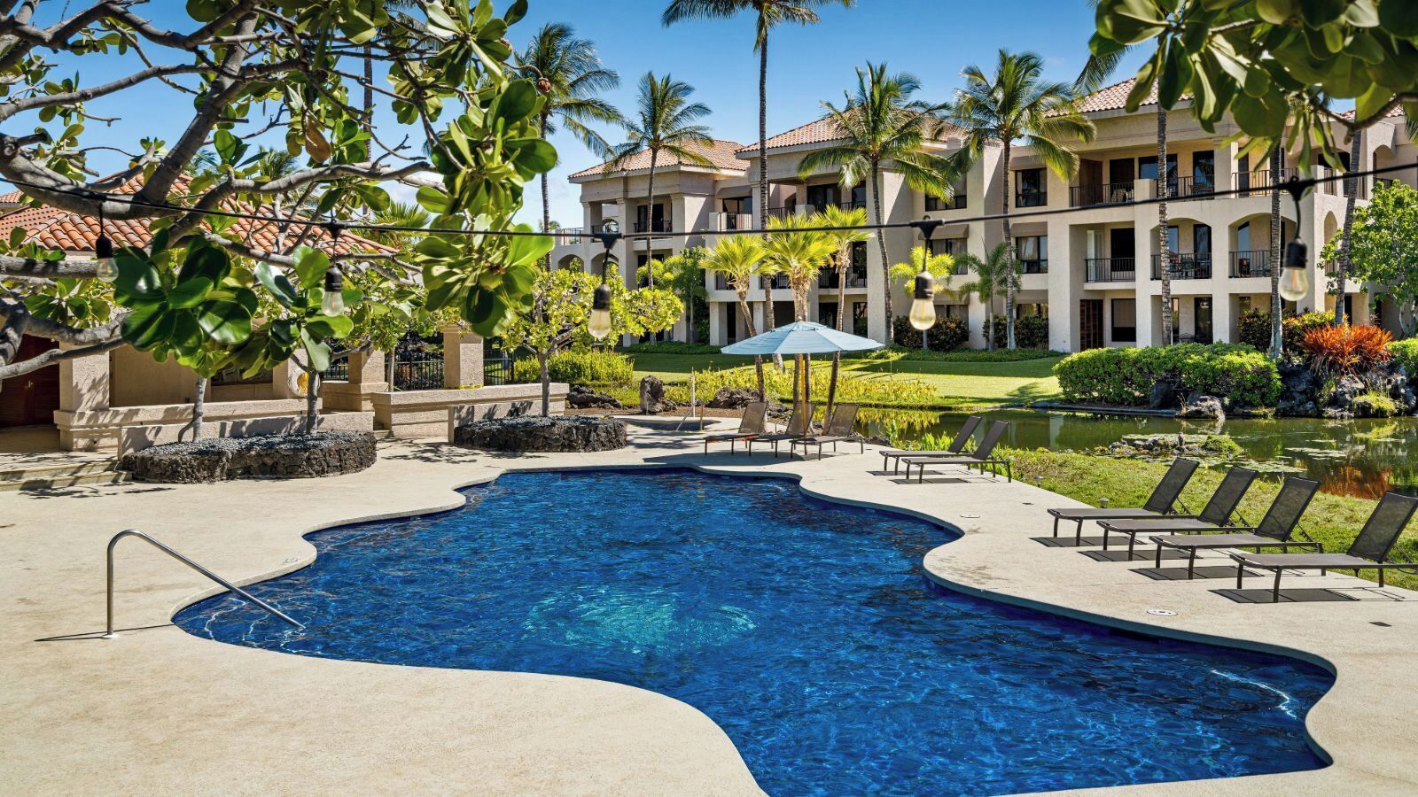 A swimming pool with lounge chairs and a building in the background.